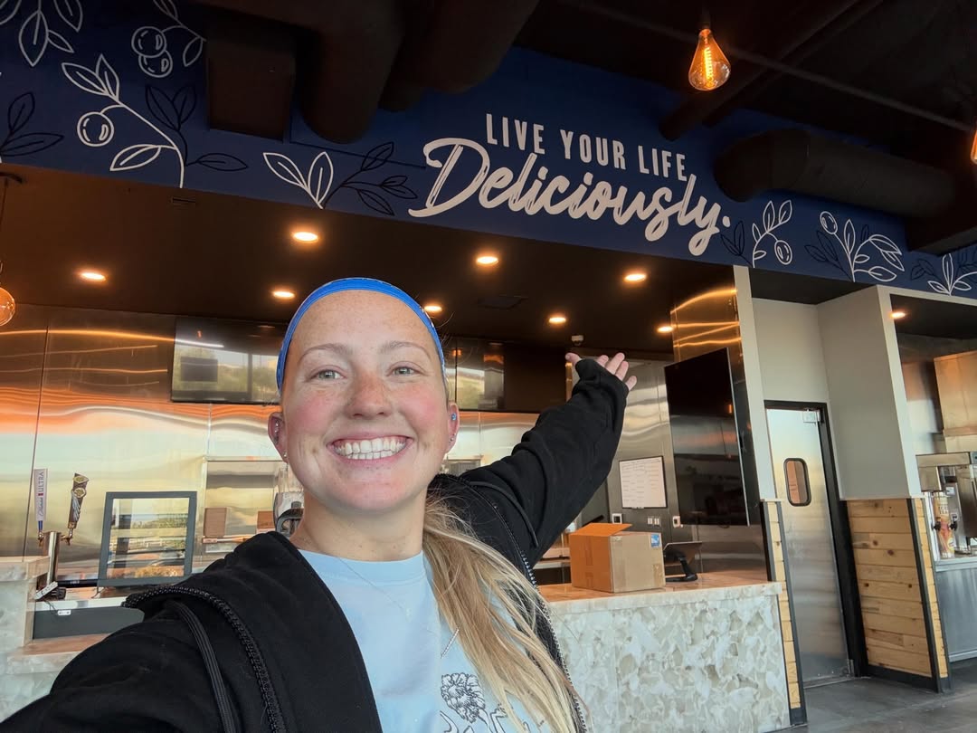Jazzy smiling beneath her Live Your Life Deliciously mural