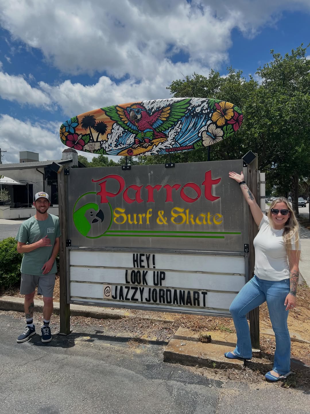 Jazzy Jordan posing beside the Parrot Surf and Skate sign and mural